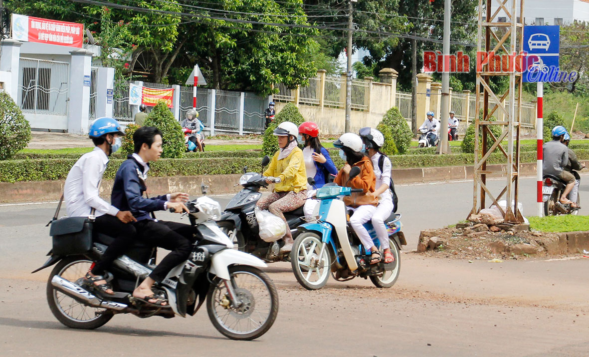 Phạt tiền từ 100.000-200.000 đồng đối với người điều khiển xe máy không đội mủ bảo hiểm. Trong ảnh, giờ tan trường của học sinh THPT ở thị xã Đồng Xoài - Ảnh: B.L