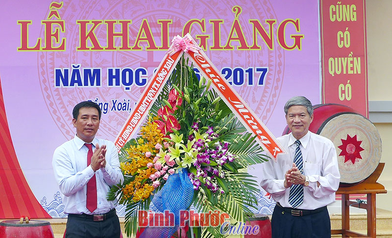 Đồng chí Huỳnh Quang Tiên, Ủy viên Ban Thường vụ Tỉnh ủy, Bí thư thị ủy Đồng Xoài tặng hoa chúc mừng nhà trường