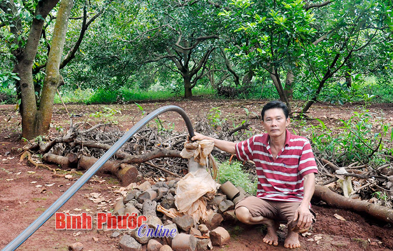 Ông Nguyễn Văn Đốm bên giếng khoan đã bị bỏ không do không có điện (ảnh nhỏ bên dưới).