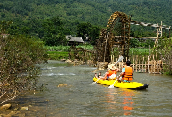 Du khách chèo thuyền trên suối.
