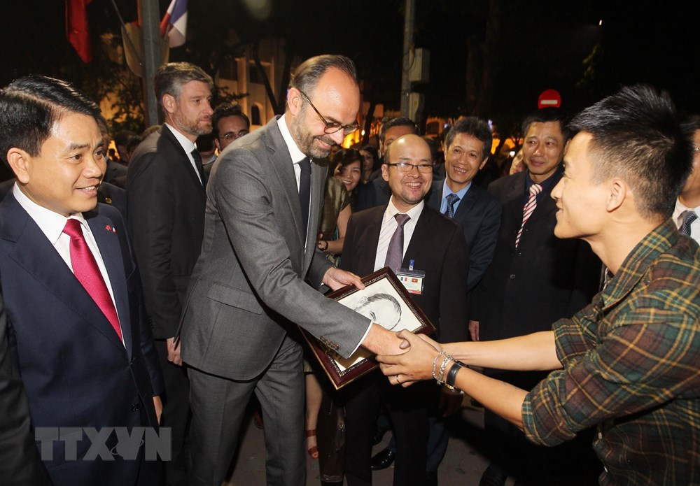 Thủ tướng Pháp Édouard Philippe nhận bức ký họa chân dung do một họa sỹ tại phố đi bộ hồ Hoàn Kiếm vẽ tặng. (Ảnh: Lâm Khánh/TTXVN)