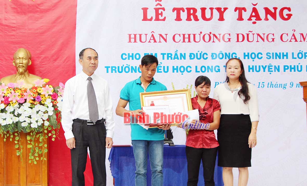 Phó chủ tịch UBND tỉnh Nguyễn Tiến Dũng trao Huân chương Dũng cảm của Chủ tịch nước truy tặng em Trần Đức Đông, học sinh lớp 2 Trường tiểu học Long Tân (Phú Riềng) đã quên mình cứu bạn